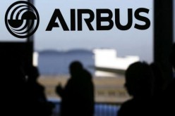 People are silhouetted past a logo of the Airbus Group during the Airbus annual news conference in Colomiers, near Toulouse, on Jan. 13, 2015.