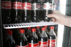 A customer takes a bottle of Coca-Cola from a grocery store fridge in Melbourne