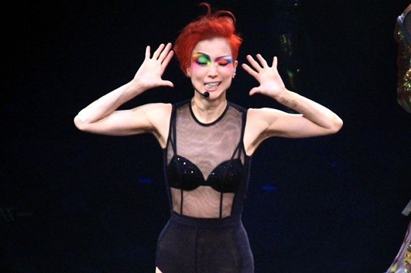 Sammi Cheng in funky makeup and hairdo and a see-through top while performing a part in her latest concert tour. 