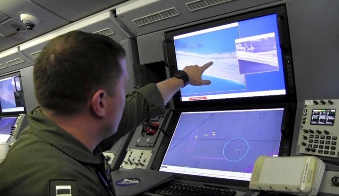 A U.S. Navy crewman aboard a P-8A Poseidon surveillance aircraft views a screen purportedly showing Chinese construction on the reclaimed land of Fiery Cross Reef in the disputed Spratly Islands.