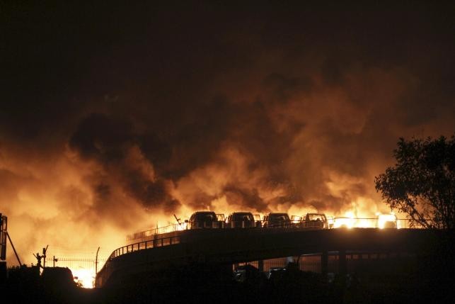 Vehicles are seen burning after blasts at Binhai New District in Tianjin, China, Aug. 13, 2015.
