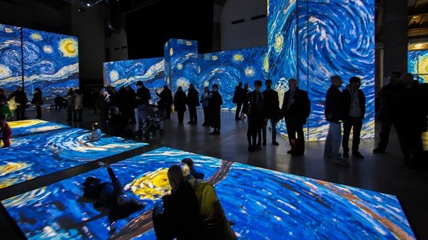 Visitors at the exhibit “Van Gogh Alive – The Experience” examine the artist's famous "The Starry Night" as flashed simultaneously on the different screens and on the bare floor.