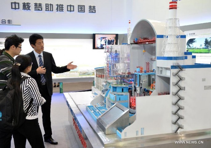 A staff member gives an introduction of the experimental fast reactor to visitors in front of a model during an exhibition in Beijing, China, April 15, 2014.