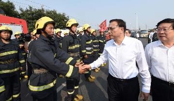 A firefighter shakes hands with Premier Li Keqiang during the Chinese leader's visit in Tianjin on Sunday, Aug. 16.