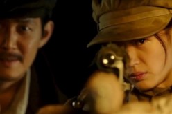 Jun Ji-hyun aims at a target while Lee Jung-jae observes in the background in the film 
