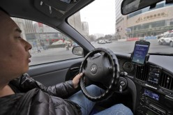 A taxi driver checks his two smartphones for potential customers in Beijing, Feb. 18, 2014. 