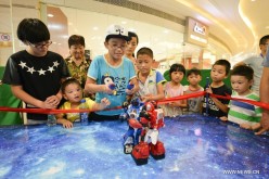 Children watch robots fight with each other at a robot show in Hefei, capital of east China's Anhui Province, Aug. 23, 2015. 
