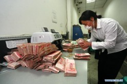 A bank staff counts cash in Suining, southwest China's Sichuan Province, Dec. 5, 2011.