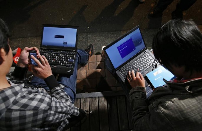 Men surf the Internet using their laptops and smartphone.