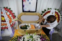 A staff member from a pet funeral company grooms a deceased pet dog inside a memorial hall at Minhang District in Shanghai on Aug. 29, 2015. 