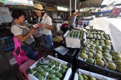 Gao Yufen (2nd L), a WeChat shop owner, bargains with a fruit vendor in Haikou, Hainan Province, on June 17, 2015. Gao is one of millions who use Wechat to bring in customers.
