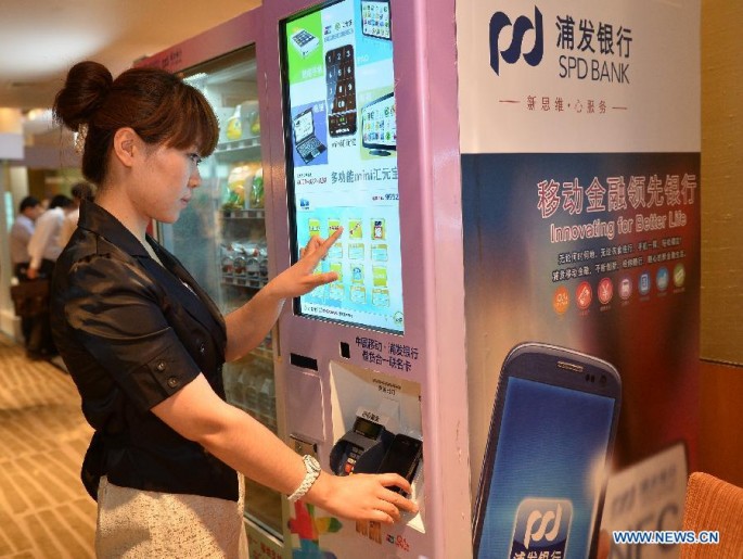 A staff member shows how to use a mobile phone to pay through a vending machine in Beijing, on June 9, 2013.