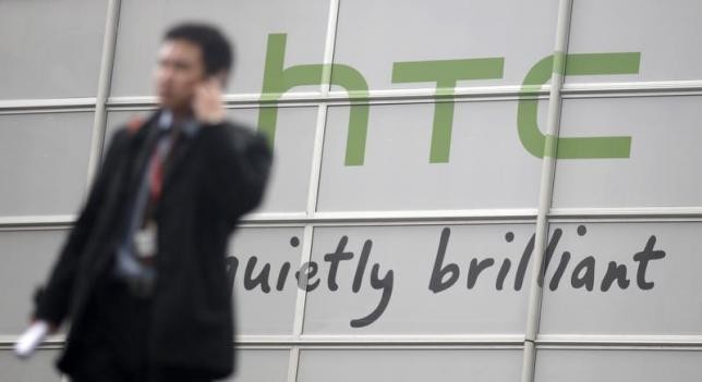 A man walks past an establishment with an HTC logo.