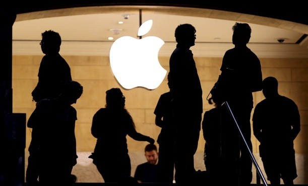 Customers stand beneath an Apple logo.