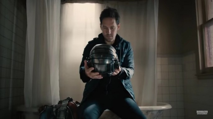 Paul Rudd in his character "Scott" is examining the "Ant-Man" outfit after he stole it.