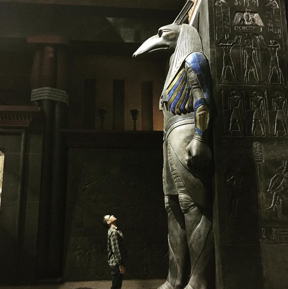 Bryan Singer looks up at a statue of an Egyptian god. 