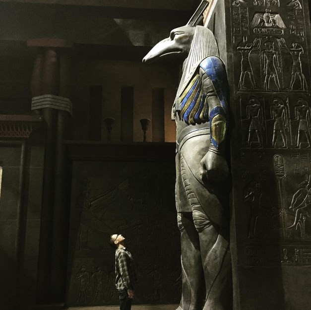 Bryan Singer is looking at an Egyptian god statue at the set of his "X-Men: Apocalypse."