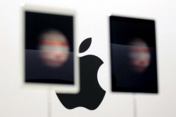 The Apple logo is seen behind a pair of Apple iPad Pros on display in San Francisco, California, Sept. 9, 2015.