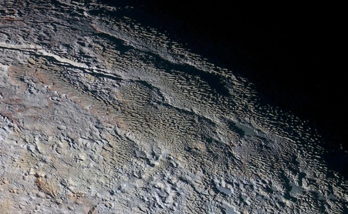In this extended color image of Pluto taken by NASA’s New Horizons spacecraft, rounded and bizarrely textured mountains, informally named the Tartarus Dorsa, rise up along Pluto’s day-night terminator and show intricate but puzzling patterns of blue-gray 