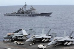 U.S. fighter jets stand by at the upper deck of a USS George Washington aircraft carrier while a U.S. Cowpens ship passes by the South China Sea, Sept. 3, 2010.