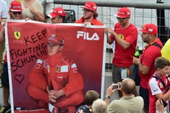 A man takes a photograph of Scuderia Ferrari's supporters as they hold a banner that reads, 'Keep fighting Schumi ' referring to former F1 legend Michael Schumacher, severely injured in December 2013 in a skiing accident in France, at the Autodromo Nazion