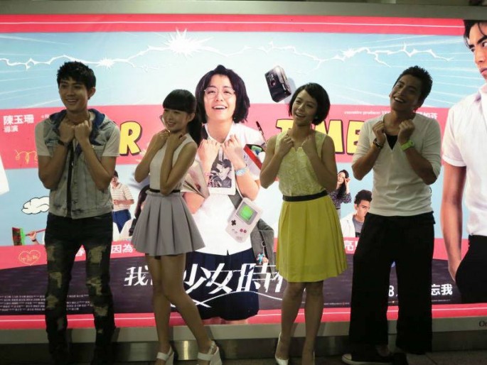 The cast of "Our Times" poses in front of the film's poster.