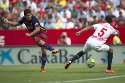 Luis Suarez (L) of FC Barcelona strikes the ball over Timothee Kolodziejczak (R) of Sevilla.
