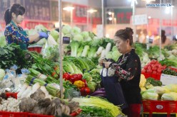 A resident purchases vegetables at a market in Shijiazhuang, north China's Hebei Province, Oct. 13, 2015.