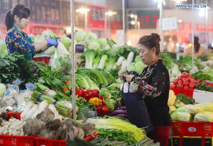 A resident purchases vegetables at a market in Shijiazhuang, north China's Hebei Province, Oct. 13, 2015.
