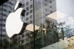 Employee look out while standing next to an Apple Inc. logo displayed at the company's store during the sales launch of the iPhone 6s and iPhone 6s Plus at the IAPM shopping mall in Shanghai, China, on Friday, Sept. 25, 2015.