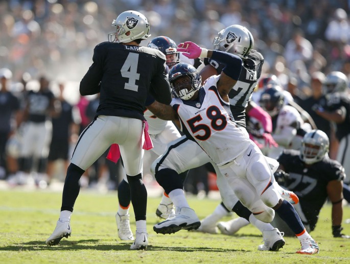 Oakland Raiders quarterback Derek Carr (#4) is sacked by Denver Broncos' Von Miller (#58).