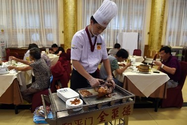 A chef serves Peking duck to customers in a Beijing restaurant.
