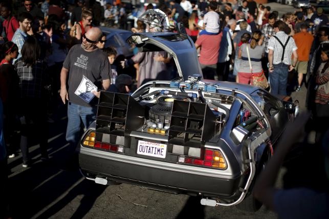 People pose for photos next to a DeLorean car outside the Burger King from the film "Back to the Future Part II", in Los Angeles, California.