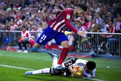 Atletico Madrid winger Yannick Carrasco is tripped by Valencia defender João Cancelo.