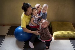 A Chinese care worker holds children on her lap as she cares for them at a foster care center in Beijing, April 2, 2014.