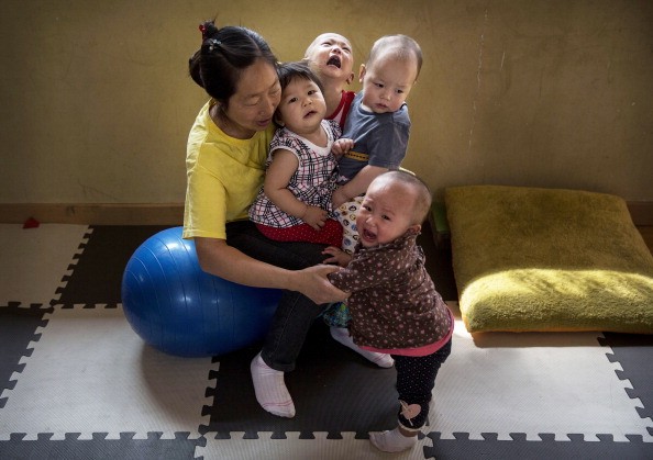 A Chinese care worker holds children on her lap as she cares for them at a foster care center in Beijing, April 2, 2014.