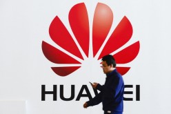 A worker passes by the Huawei logo at a trade fair in Hanover, Germany, in this March 9, 2014 photo.