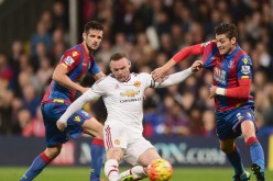 Manchester United striker Wayne Rooney (middle) shoots the ball on goal against two Crystal Palace defenders.