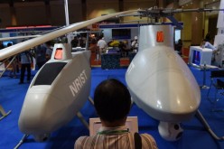 An exhibit attendee observes two Chinese-made drone helicopters in Beijing last year.