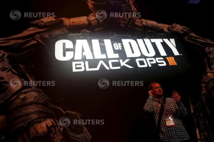 An attendee stands in front of the "Call of Duty Black Ops III" video game poster at the Sony PlayStation booth