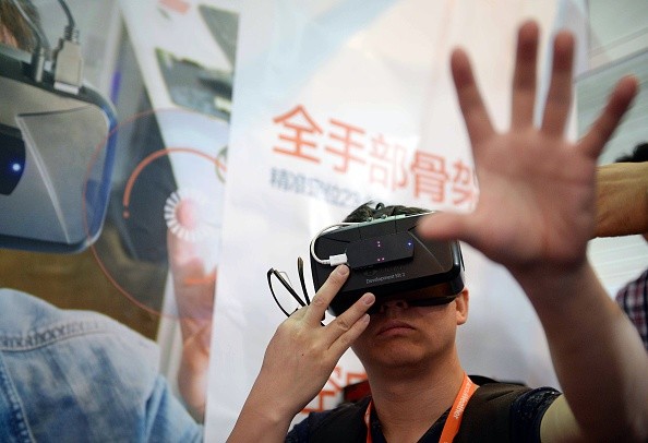 A man, donning the Oculus Rift development kit 2, tries to "touch" the virtual world he is in at the  Consumer Electronics Show (CES) in Asia in Shanghai in May. 