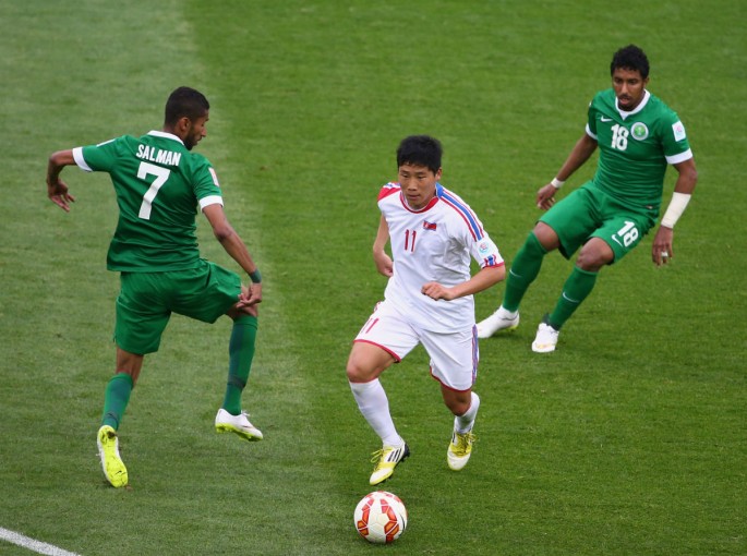 North Korea striker Jong Il-gwan goes in between two Saudi Arabia defenders.
