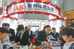 Staff members of Anbang Insurance Group Co. Ltd. explain their policies to prospective clients at an international finance expo in Beijing. 
