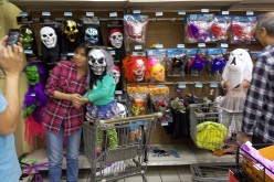 A mother carries her son while the boy wears a Halloween mask at a shopping store in Wuhan, Hubei Province, Oct. 26, 2015.
