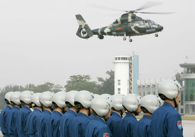 Outgoing Chinese People's Liberation Army (PLA) helicopter pilots watch as a helicopter full of new air force personnel arrives at a ceremony in Hong Kong on Nov. 25, 2007.