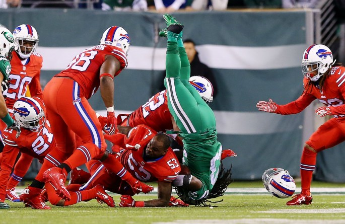 New York Jets running back Chris Ivory (in green) is tackled by Buffalo Bills defenders.
