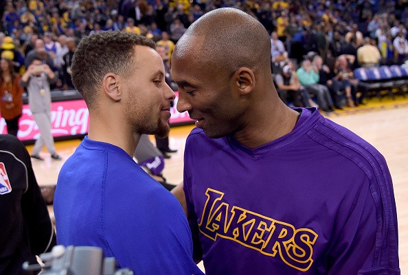Stephen Curry of the Golden State Warriors meets at center court with Kobe Bryant of the Los Angeles Laker prior to the start of their NBA basketball game at ORACLE Arena on November 24, 2015 in Oakla