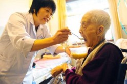 A caregiver attends to an elderly at a nursing home in Jinan, capital of Shandong Province.