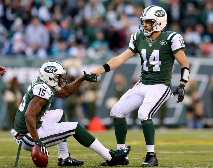 New York Jets quarterback Ryan Fitzpatrick (#14) helps up wide receiver teammate Brandon Marshall after a play against the Miami Dolphins.
