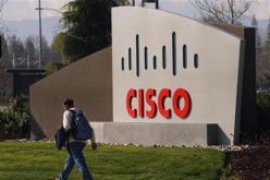 A pedestrian walks past the Cisco logo at the technology company's campus.